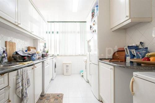a kitchen with white cabinets and a large window at Cascais Luxury Top Floor Apt in Cascais