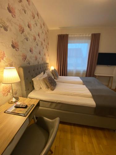 a bedroom with a bed with a desk and a window at Smålandsstenar hotell in Smålandsstenar