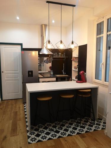 une cuisine avec un grand îlot et des tabourets de bar dans l'établissement Charme et confort en plein centre historique, à Nantes
