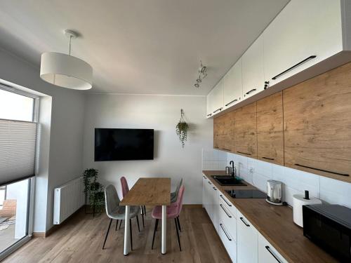 Il comprend une cuisine avec une table et des chaises ainsi qu'une télévision. dans l'établissement Apartament w chmurach, à Toruń