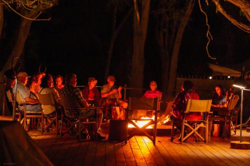 a group of people sitting around a fire at night at Soroi Larsens Camp in Buffalo Springs  National Reserve