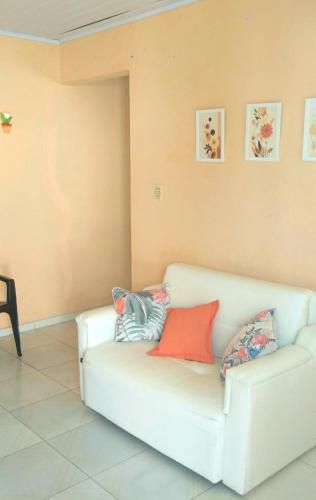 un sofá blanco en una sala de estar con almohadas en Casa de praia Barra do Ribeira Juréia Iguape SP, en Iguape