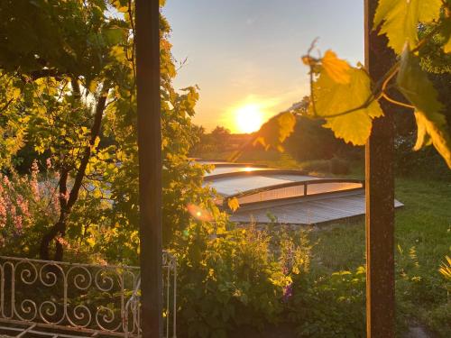 a view of the sunset from the porch of a house at La Jolie Longère Fleurie Lodge avec piscine et jardin in Le Gué-dʼAlléré
