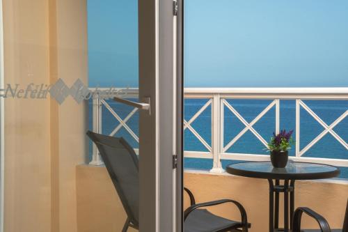 einen Balkon mit einem Tisch und Meerblick in der Unterkunft Nefeli Beach - living by the sea in Argassi