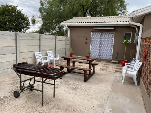 a patio with a table and chairs and a barbecue at Little Miracle in Beaufort West
