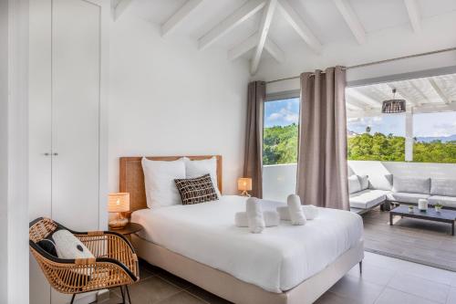 a bedroom with a white bed and a living room at Le Domaine de l'Anse Mitan in Les Trois-Îlets