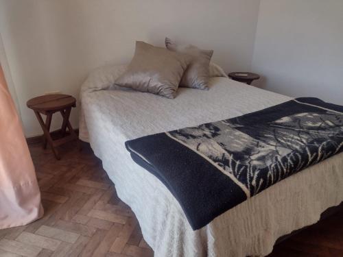 1 cama con manta blanca y negra y 2 mesas en Edificio Bianini en Rosario