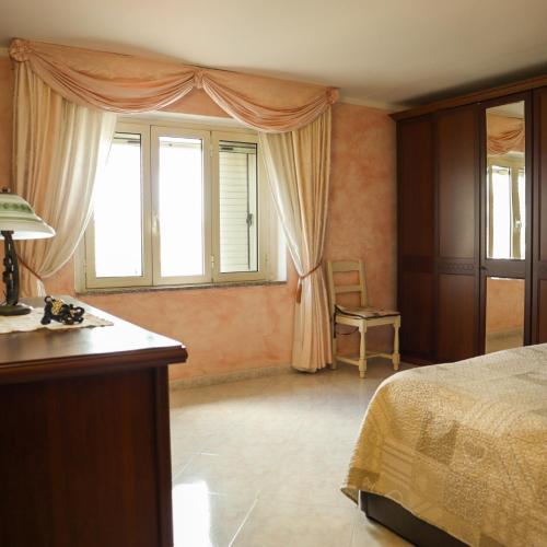 a bedroom with a bed and a desk and a window at Appartamento La Vista in Budoni