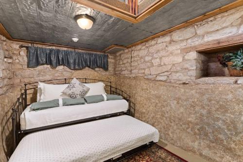 two beds in a room with a stone wall at #6 The Root Cellar in New Braunfels