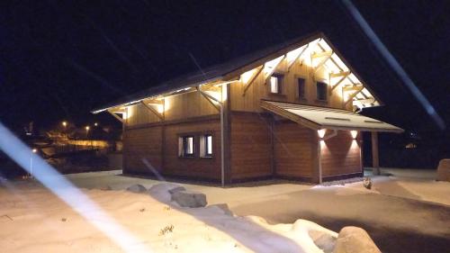 un bâtiment avec des lumières au-dessus de celui-ci la nuit dans l'établissement CHALET LA LUNELLE sauna, à La Bresse
