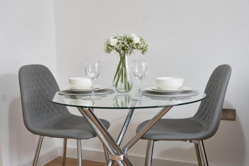 a glass table with two chairs and a vase of flowers at Luxury Central Apartment - Smart TV - Fast WIFI - Near Utilitia Arena in Birmingham