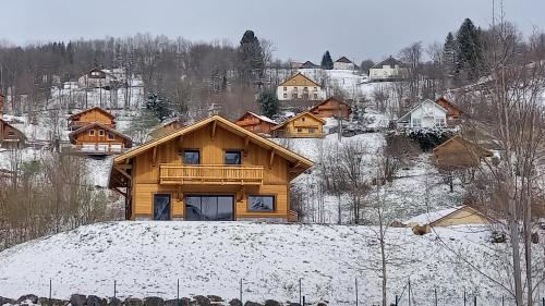 une maison en bois au sommet d'une colline enneigée dans l'établissement CHALET LA LUNELLE sauna, à La Bresse