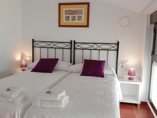 een slaapkamer met 2 witte bedden met paarse kussens bij Alojamientos Zabala La Piedra en Nájera in Nájera