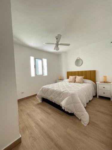 a white bedroom with a bed and a ceiling fan at Bungalow Ara in Puerto del Carmen