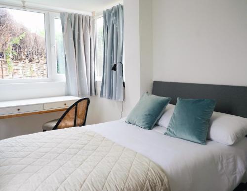 a bedroom with a bed with blue pillows and a window at Comfortable and cosy house with off-road parking in Cantley