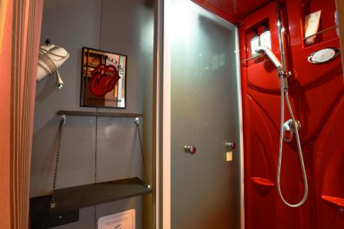 La salle de bains est pourvue d'une douche et d'une porte rouge. dans l'établissement 一棟貸し平戸俺んち, à Hirado