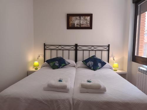 a bedroom with a large white bed with towels on it at Apartamentos La Piedra de Nájera in Nájera