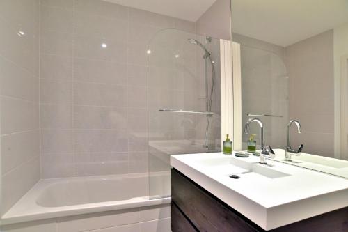 La salle de bains blanche est pourvue d'un lavabo et d'une baignoire. dans l'établissement Les Flots de Port Mer Maison tout confort pour 4 pers avec jardinet à Port Mer à Cancale à 5 min à pied de la plage Côte d'Emeraude, Ille et Vilaine, Bretagne, à Cancale