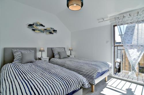 2 Betten in einem weißen Zimmer mit Fenster in der Unterkunft Les Flots de PortMer in Cancale
