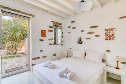 a white bedroom with a bed and a window at Great house w/ BBQ in Paros in Santa Maria