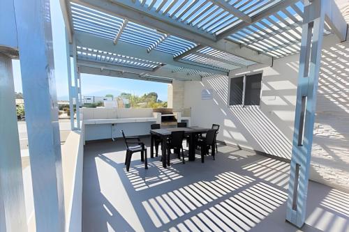 a patio with a table and chairs under a pergola at Condominio Pacífico 2800 in La Serena