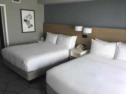 two beds in a hotel room with white pillows at DoubleTree Suites by Hilton Melbourne Beach Oceanfront in Melbourne
