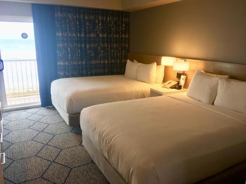 a hotel room with two beds and a window at DoubleTree Suites by Hilton Melbourne Beach Oceanfront in Melbourne