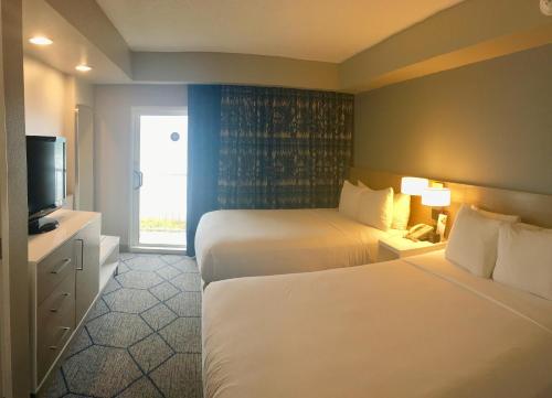 a hotel room with two beds and a television at DoubleTree Suites by Hilton Melbourne Beach Oceanfront in Melbourne