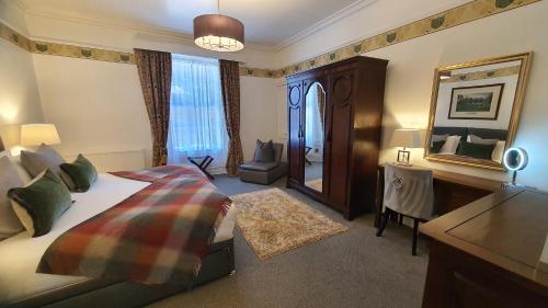 1 dormitorio con cama, escritorio y espejo en Dunperrogh, en St Andrews