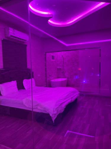 a bedroom with a bed with purple lights on it at شاليهات الشوق in As Sayl aş Şaghīr