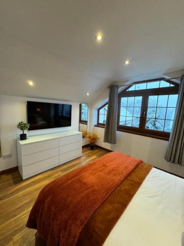 a bedroom with a large bed and a flat screen tv at 1 Sheraton Apartments in Fort William