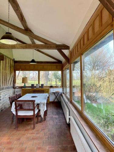 - une véranda avec une table et des fenêtres dans l'établissement Cottages Normands (deux maisons), à Houlgate
