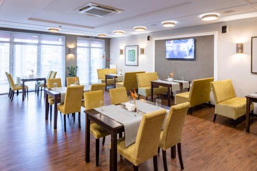 a dining room with tables and yellow chairs at Taurus Hotel & SPA in Lviv