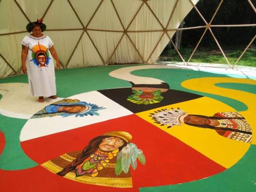 a woman standing on a floor with a painting on it at Aldeia Gaia Chalés in Teresópolis