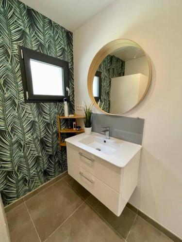 une salle de bain avec un lavabo blanc et un miroir dans l'établissement Villa moderne avec jacuzzi, au pied de la plage, à Labenne