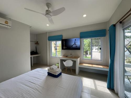 a bedroom with a bed and a desk and windows at Sand Terrace Beach Bungalows in Baan Tai
