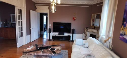 sala de estar con sofá blanco y TV en LE NODIER en Lons-le-Saunier