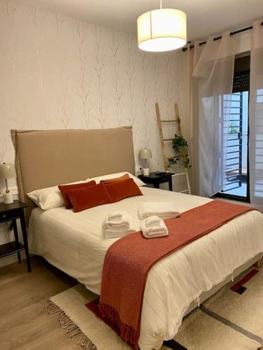 een slaapkamer met een groot wit bed met rode kussens bij Nuevo Moderno Apartamento de Lujo in Sevilla