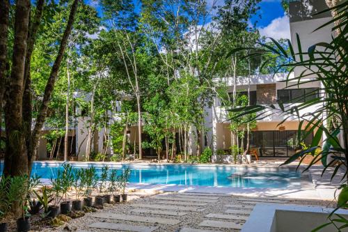 a swimming pool in front of a building with trees at Aqua Viva, Pool, AC, Internet, Beach club in Bacalar
