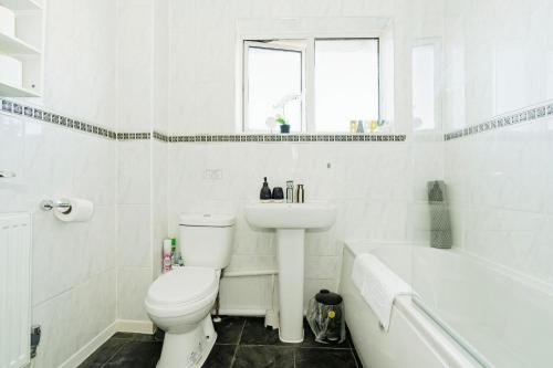 a bathroom with a toilet and a sink and a tub at Gema Home - Charming Canterbury Home with private parking perfect for vans in Kent