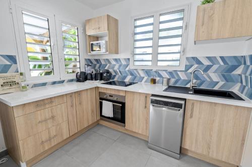 cocina con armarios de madera, fregadero y lavavajillas en Villa Kaz Kreyol, en Les Anses-dʼArlet