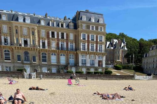 pessoas deitadas na praia em frente a um grande edifício em 3 Pieces BORD DE MER- Trouville em Trouville-sur-Mer