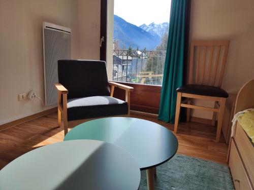 - un salon avec une table, une chaise et une fenêtre dans l'établissement Evasion Pyrénéenne, à Luchon