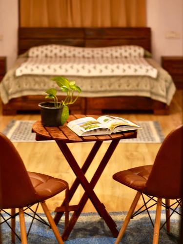- une table avec un livre et un lit dans une chambre dans l'établissement The Flying Squirrel Bandhavgarh, à Umariā