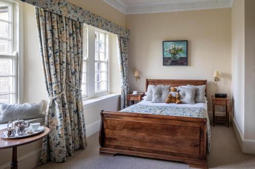 a bedroom with a bed with a teddy bear sitting on it at Swinton Park in Masham