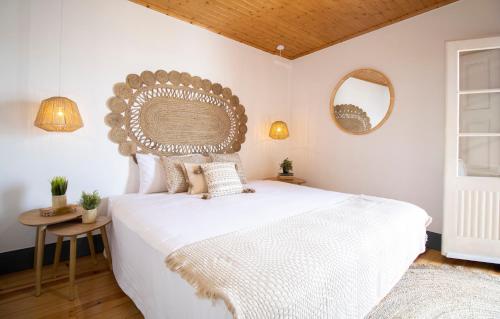 a bedroom with a large white bed and two mirrors at Sé Velha Suites in Coimbra