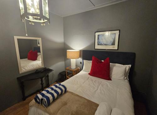 1 dormitorio con cama con almohadas rojas y espejo en Angel Bay, 129 Nkwazi Drive, Zinkwazi, en Zinkwazi Beach