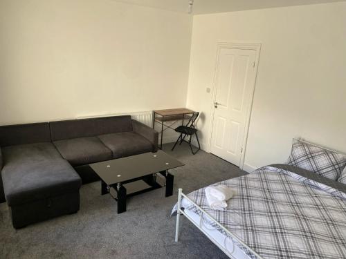 ein Wohnzimmer mit einem Sofa, einem Tisch und einem Bett in der Unterkunft SWEET DREAMS 2 in Luton