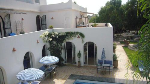 a white house with two tables and a swimming pool at Villa Daba in Ghazoua