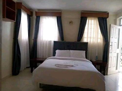 a bedroom with a large bed in front of windows at Sagada Resort Lamuria in Nyeri